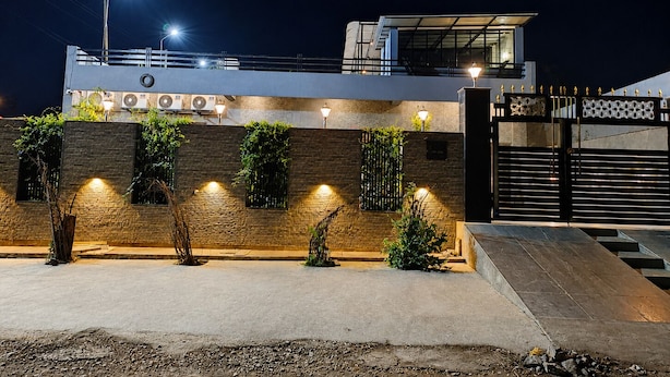 A modern building with a flat roof, a gated entrance, and outdoor lighting. - Shubh Ashray (UDAIPUR)
