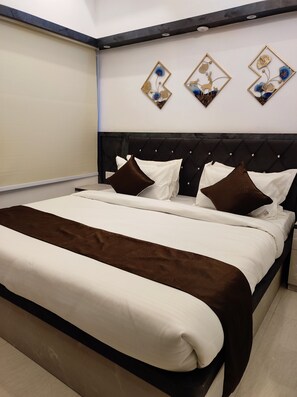 A neatly made bed with a brown throw blanket, a dark headboard, and three wall-mounted decorative pieces.