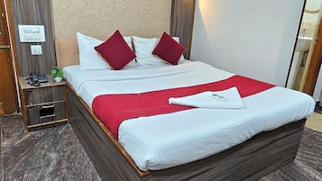 Habitación de hotel con una cama grande, cabecera de madera, mesita de noche con teléfono y lámpara de pared.