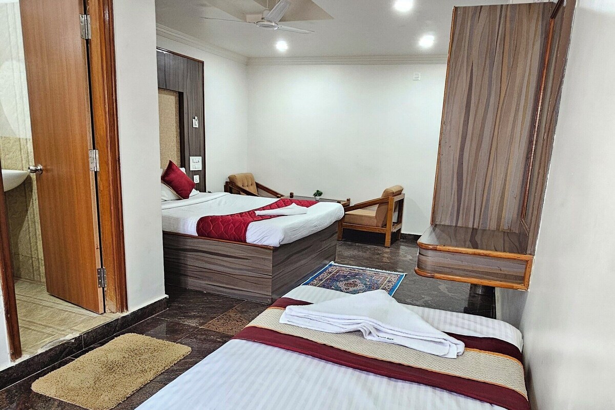 A hotel room with a bed, a desk, a chair, a mirror, and a ceiling fan.