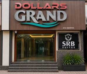 Entrada de un hotel con un letrero que dice 'Dollars Grand' y 'SRB Suites'.