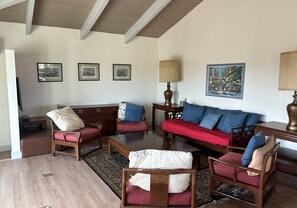 A living room with a wooden ceiling, a red sofa, and a coffee table. There are three framed pictures on the wall. - Vineyard Hill — Life’s an Adventure. Stay Somewhere Worth the Journey. (Forestville)