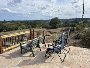 Eine Terrasse mit Steinboden, Holzgeländer und einer Bank.