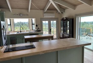 A kitchen with a large island, a built-in oven, and a view of the outdoors through large windows. - Vineyard Hill — Life’s an Adventure. Stay Somewhere Worth the Journey. (Forestville)