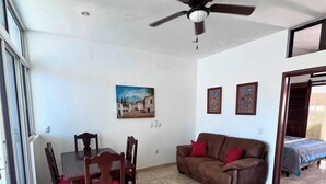 A room with a dining table and chairs, a brown sofa, a ceiling fan, and a painting on the wall. - Perfect retreat 2 blks from beach in Villa Obregón neighbourhood  Melaque! (San Patricio)