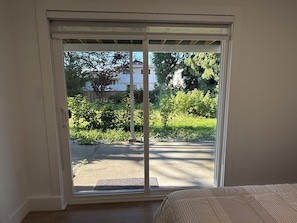 Quarto com porta de vidro deslizante que dá para um jardim.