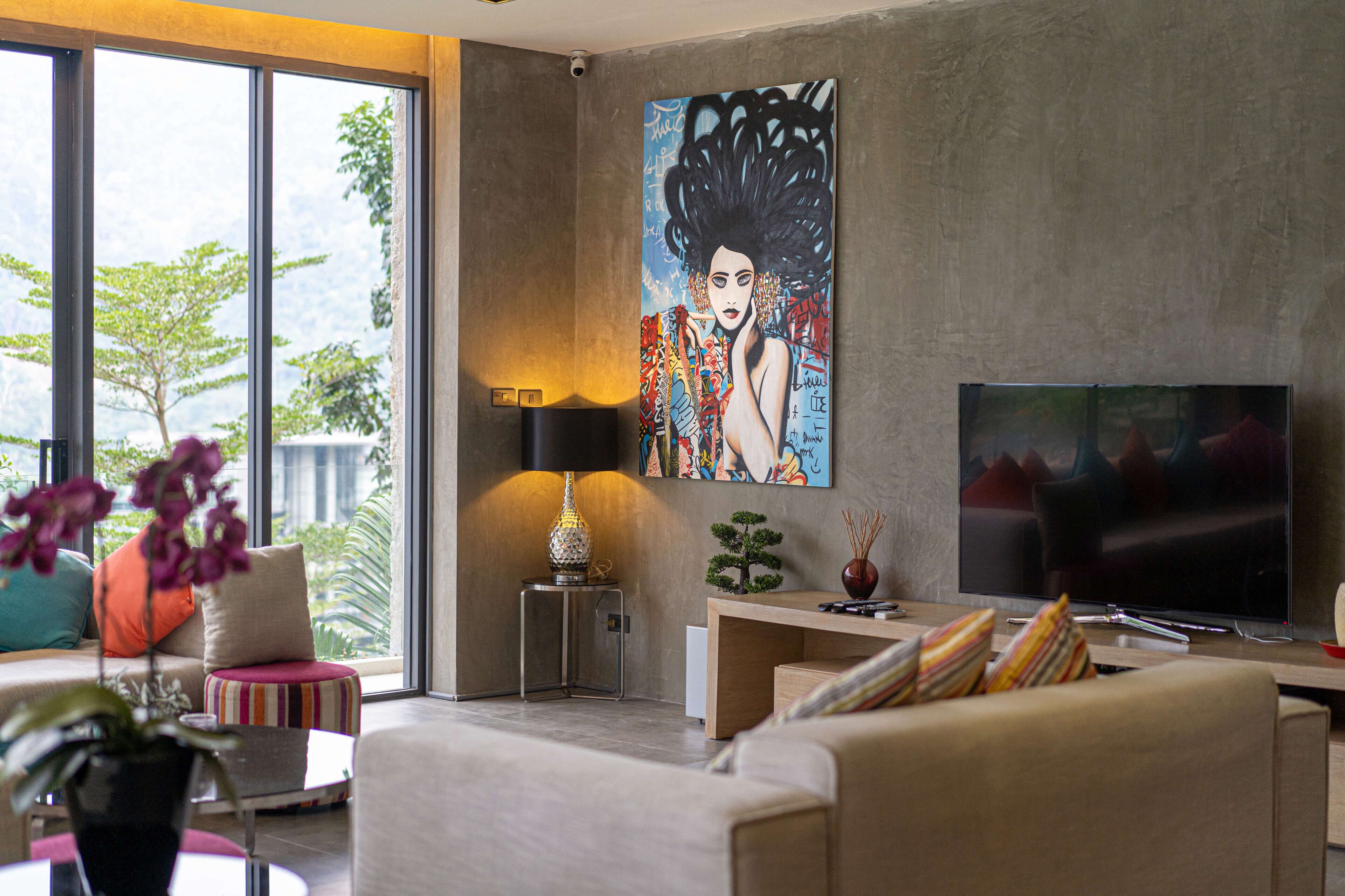 Een moderne woonkamer met een grote televisie, een schilderij aan de muur en uitzicht op het groen.