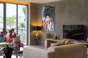 A modern living room with a large TV, a painting on the wall, and a view of the outdoors. - Art Deco 3 BR Pool Villa Kamala NP1 (Kathu)