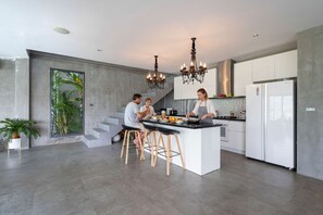 Una cocina moderna con una isla central, taburetes de bar y una escalera que sube a un nivel superior.