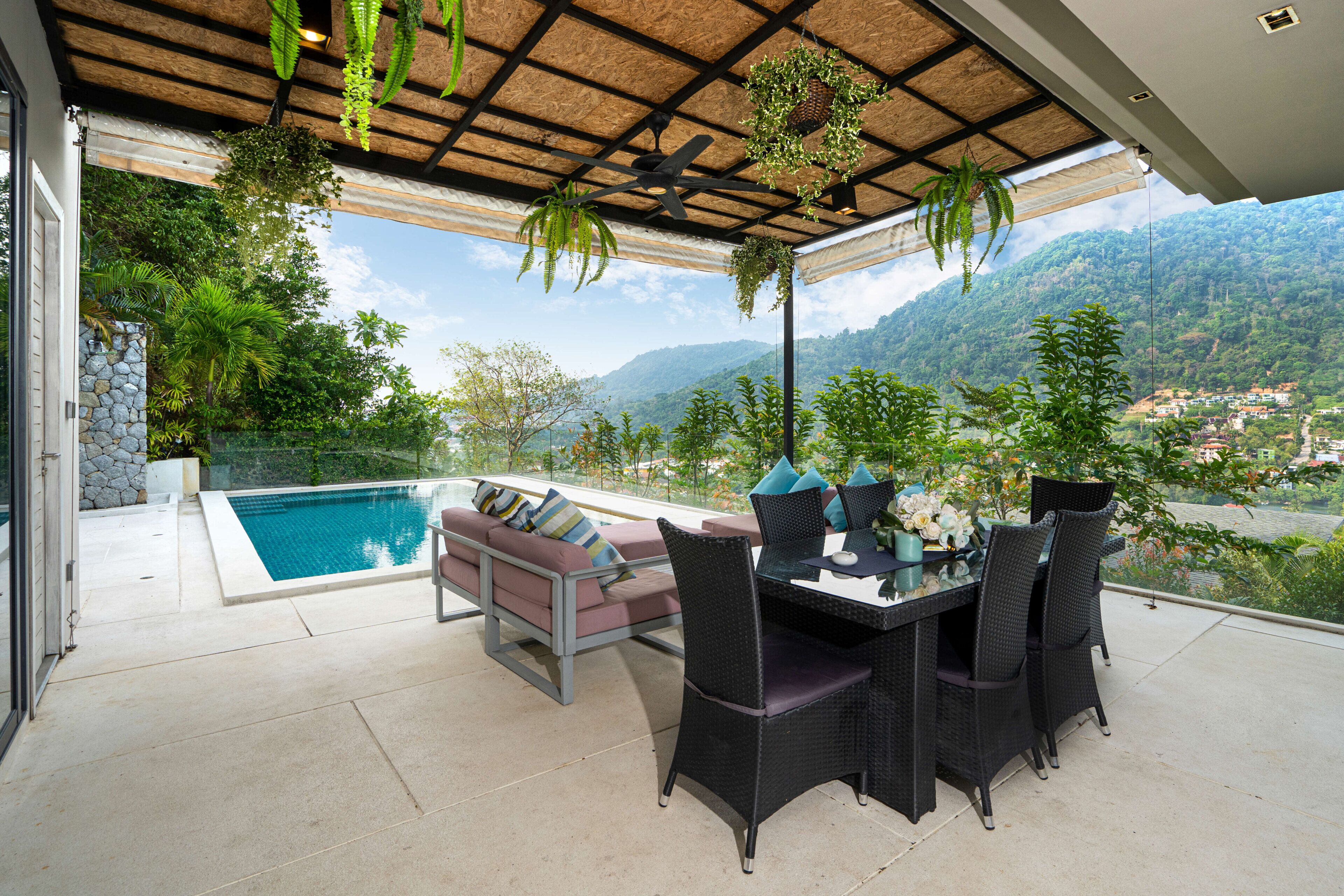 Una terraza con piscina, mobiliario exterior y vistas a un paisaje montañoso.