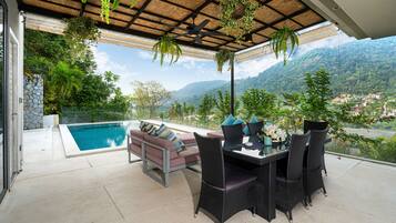 Una terraza con piscina, mobiliario exterior y vistas a un paisaje montañoso.