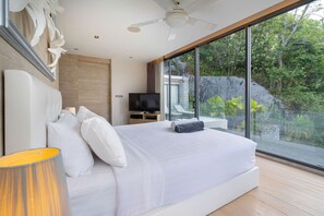 Een moderne slaapkamer met een groot bed, een televisie en uitzicht op een natuurlandschap door grote ramen.