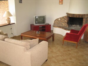 A living room with a television, a fireplace, a sofa, and a red chair. - Relaxing Holiday Home in Normandy (Courtils)