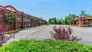 A row of motel buildings with a parking lot in front.