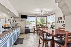 Een moderne keuken met een eethoek, een flatscreen televisie en uitzicht op buiten.