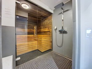 A modern shower area with a glass door, wooden panel walls, and a tiled floor. - Les Rahâs A5 by Interhome (Grimentz)