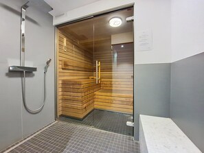 Un espace douche moderne doté d’une porte en verre, de lambris en bois et d’un pommeau de douche en métal.
