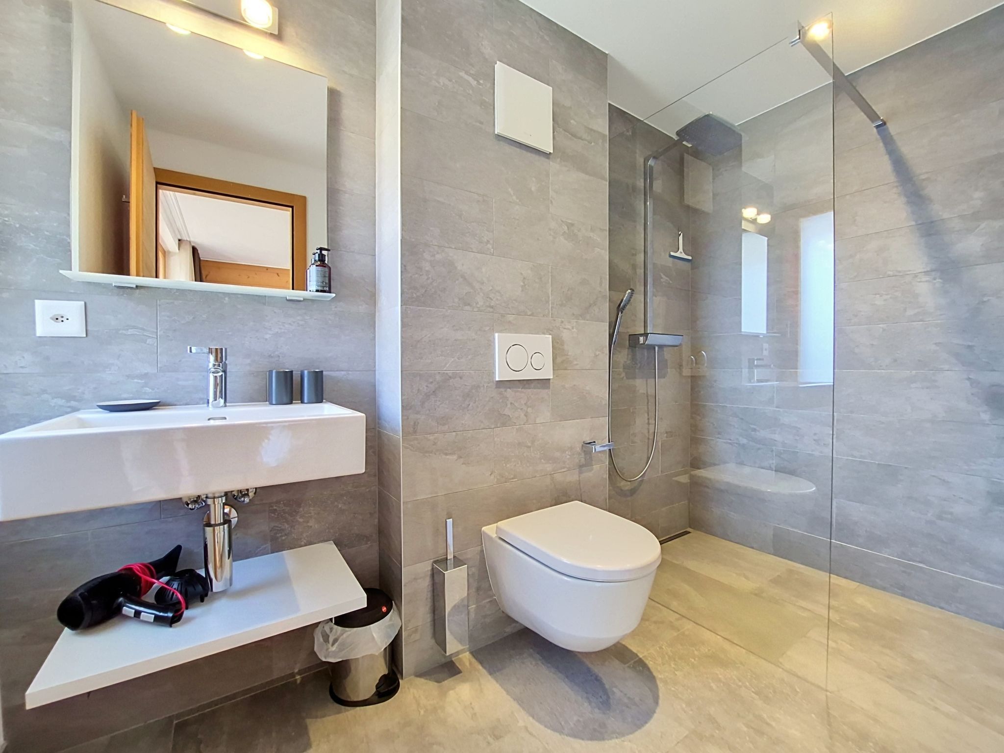 A modern bathroom with a white sink, mirror, and toilet.