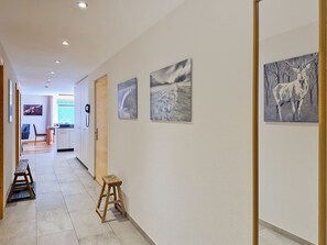 Un couloir avec un banc en bois, un petit tabouret et trois tableaux encadrés accrochés au mur.