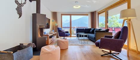 Una sala moderna con chimenea, zona de estar y vistas a las montañas.