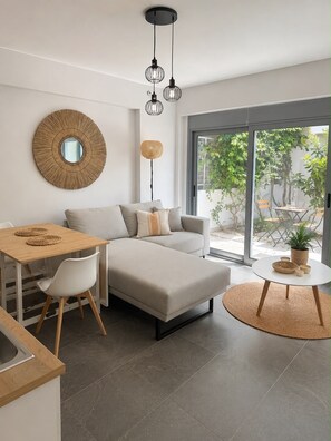 A modern living space with a sofa, dining table, and a round coffee table. - Cozy Maisonette next to Acropolis hill (Athina)
