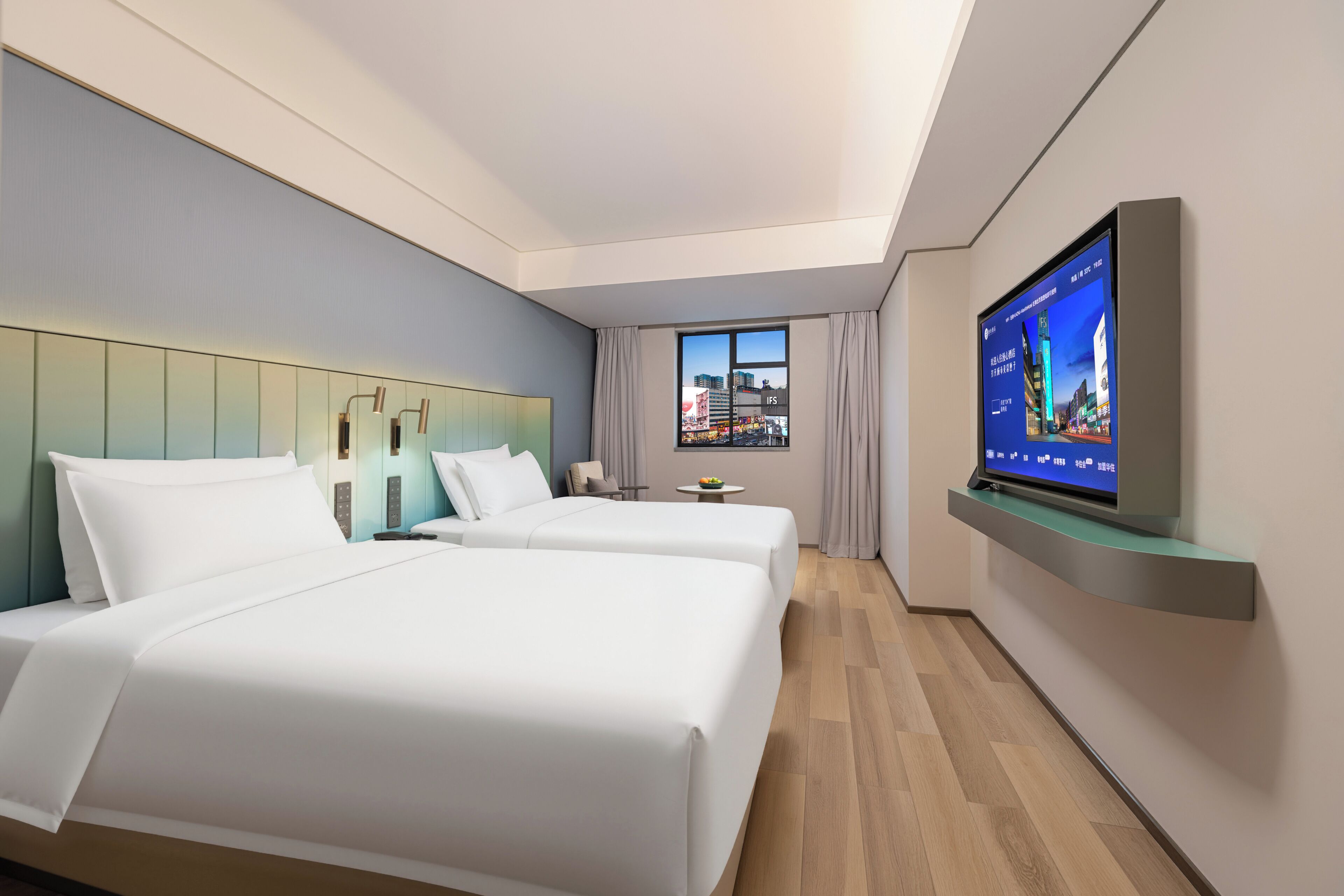 Une chambre d’hôtel avec deux lits, une télévision, une fenêtre donnant sur la ville et un design moderne.