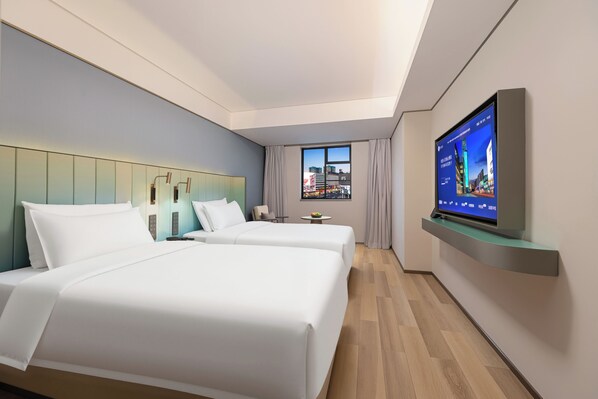 A hotel room with two beds, a television, a window with a city view, and a modern design.