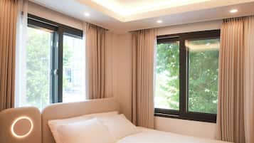 A hotel room with a bed, a chair, and windows with curtains.