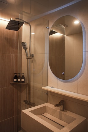 A modern bathroom with a glass-enclosed shower, a round mirror, and a built-in sink.