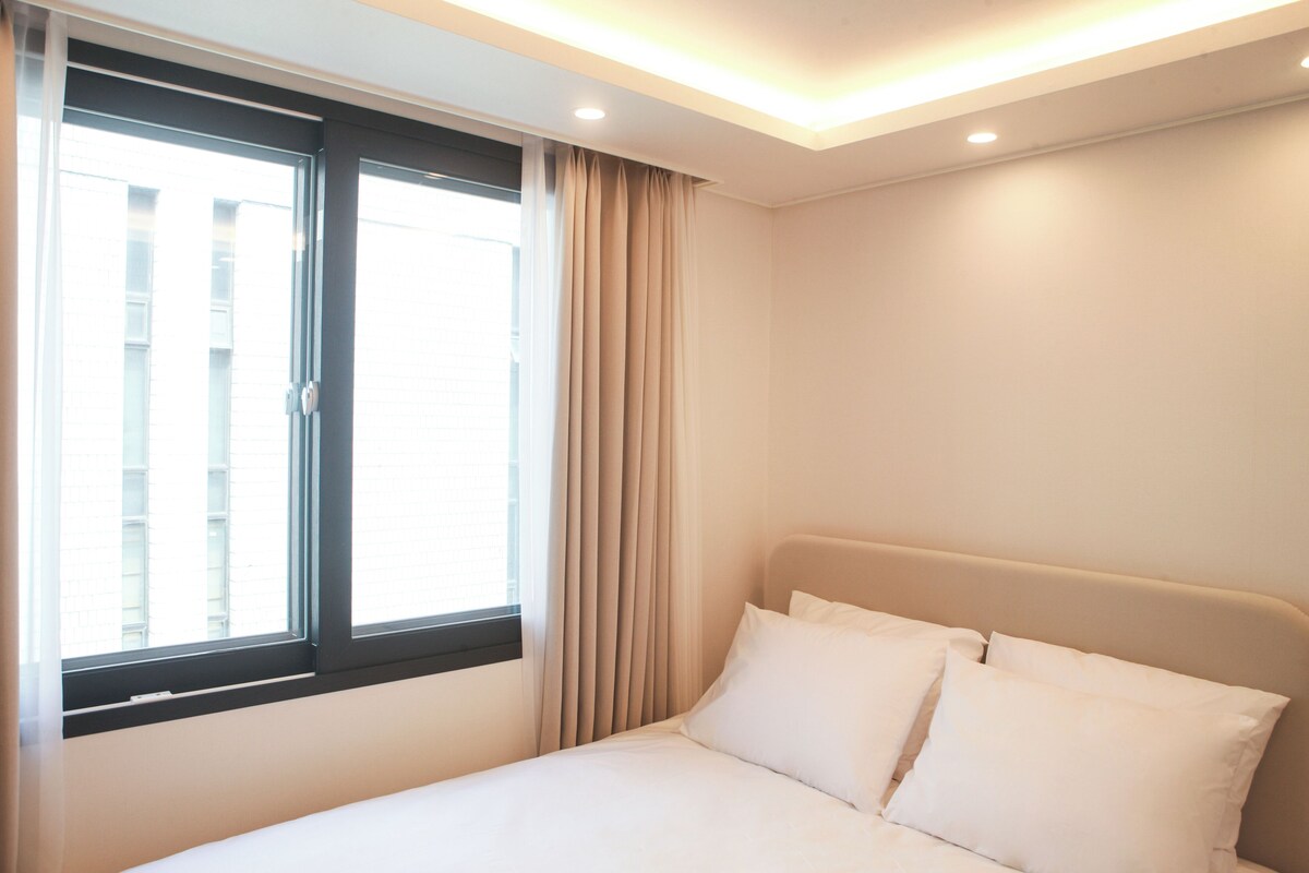 A hotel room with a bed, curtains, and a window.