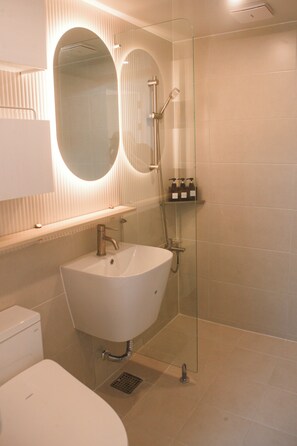 Un bany modern amb un sol lavabo, una dutxa envidriada i un mirall sobre el lavabo.