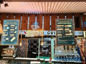 A café with a menu board, a neon sign, and a display of bottled water. - Hotel Rudra Villa (Abu Road)