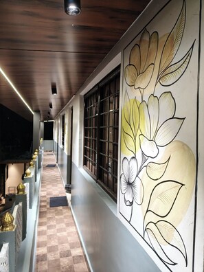 Un pasillo con suelo a cuadros, una pared con un mural floral y una serie de ventanas con barrotes.