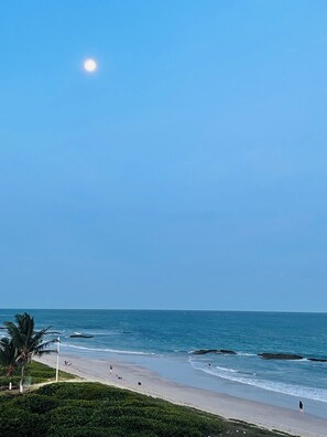 A beach with a clear sky, calm sea, and a few people. - Carneiros Beira-Mar | 2Q | Nomar Ecoliving (Tamandare)