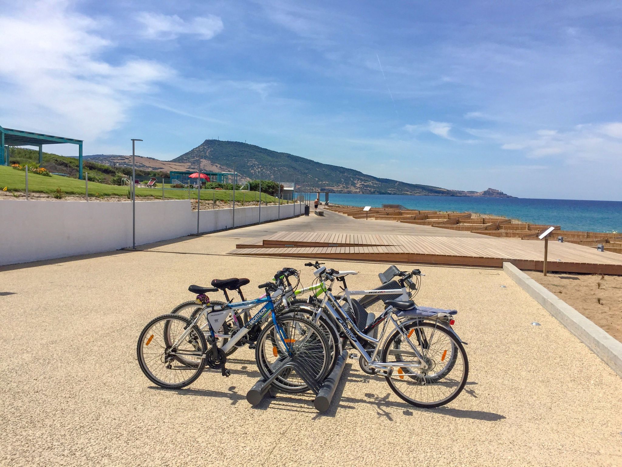 Een fietsenstalling met uitzicht op de zee en een berg op de achtergrond.