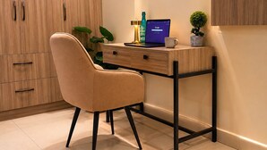 Un espacio de oficina moderno con escritorio, silla, laptop y objetos decorativos.
