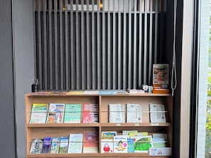 Una estantería con varios libros y revistas, una celosía de metal negro y una puerta de madera.