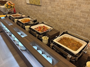 Montaje de bufé con varias estaciones de comida y un fondo de pared de ladrillo.