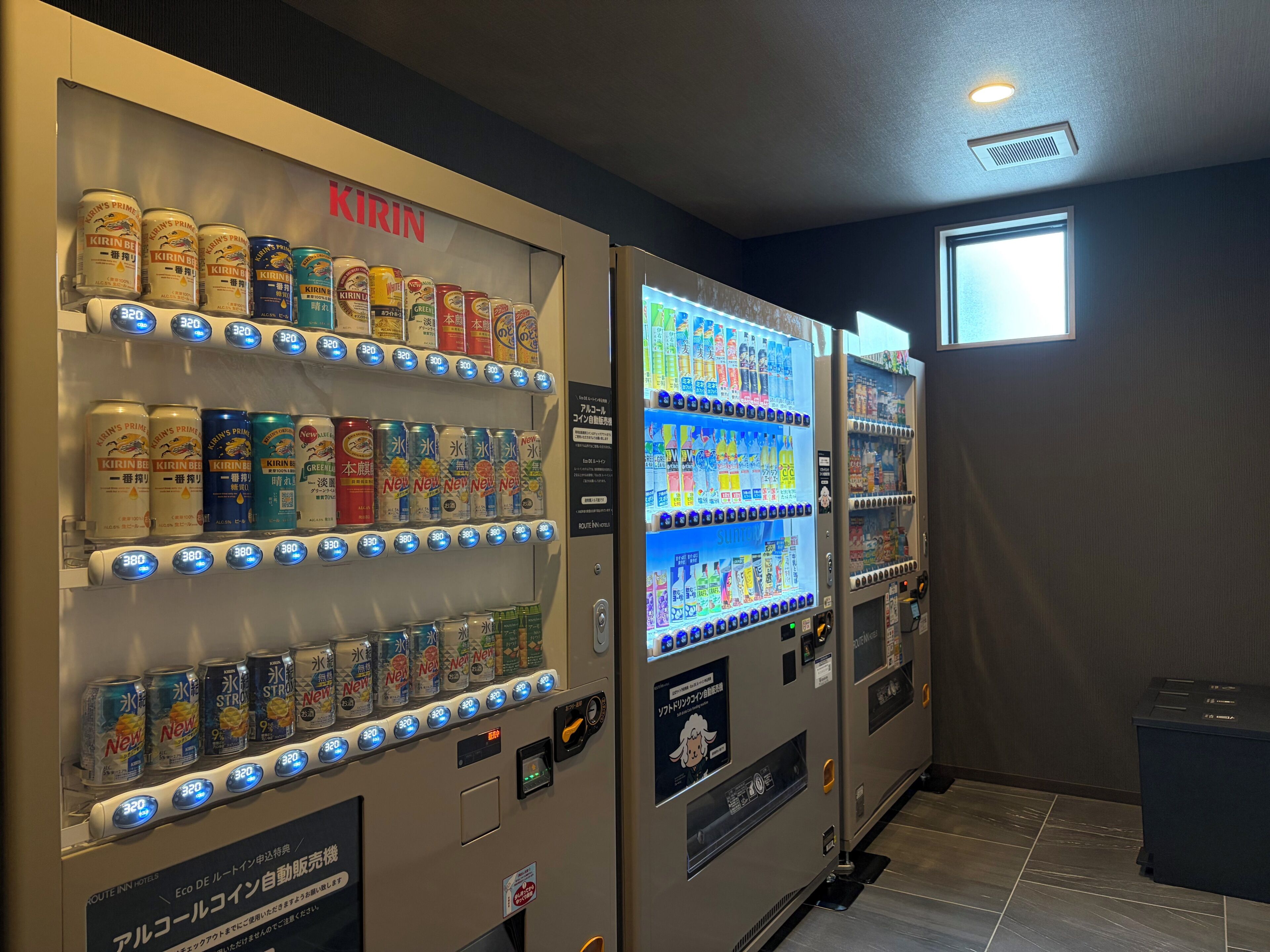 Máquinas expendedoras con diversas opciones de bebidas, un ventanal y un piso de baldosas.
