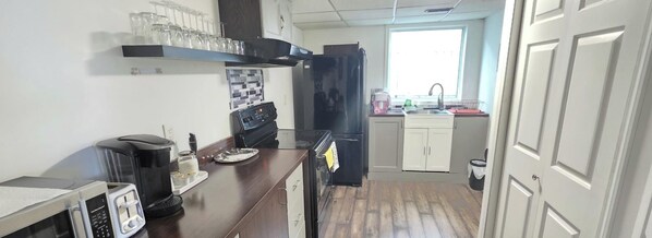 Una cocina compacta equipada con microondas, cafetera y refrigerador.