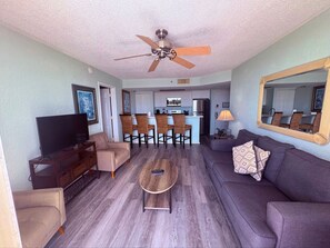 Living room featuring a sofa, TV console, and view into the kitchen counter with barstools. - Key West Paradise Condo w/ Pool, Hot Tub, Tennis (Key West)