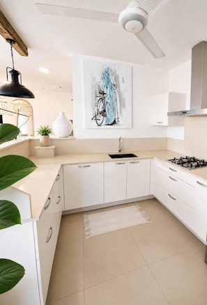 A modern kitchen with white cabinetry, a gas stove, a ceiling fan, and a painting on the wall. - Mont Choisy 3-Bedroom Villa, Grand Baie (Grand Baie)