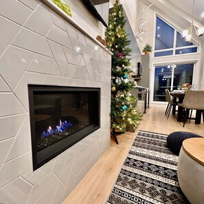 Een moderne woonkamer met een open haard, een kerstboom en een eethoek met uitzicht.