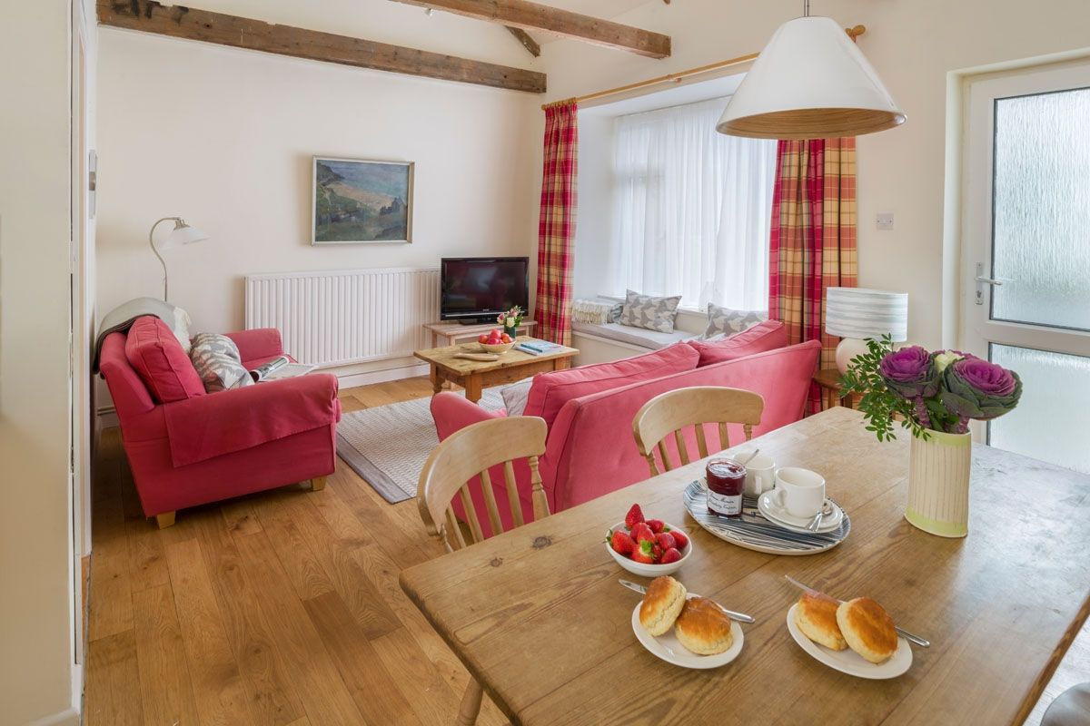 Un salon confortable avec un ensemble de canapés, une table à manger dressée et un téléviseur.