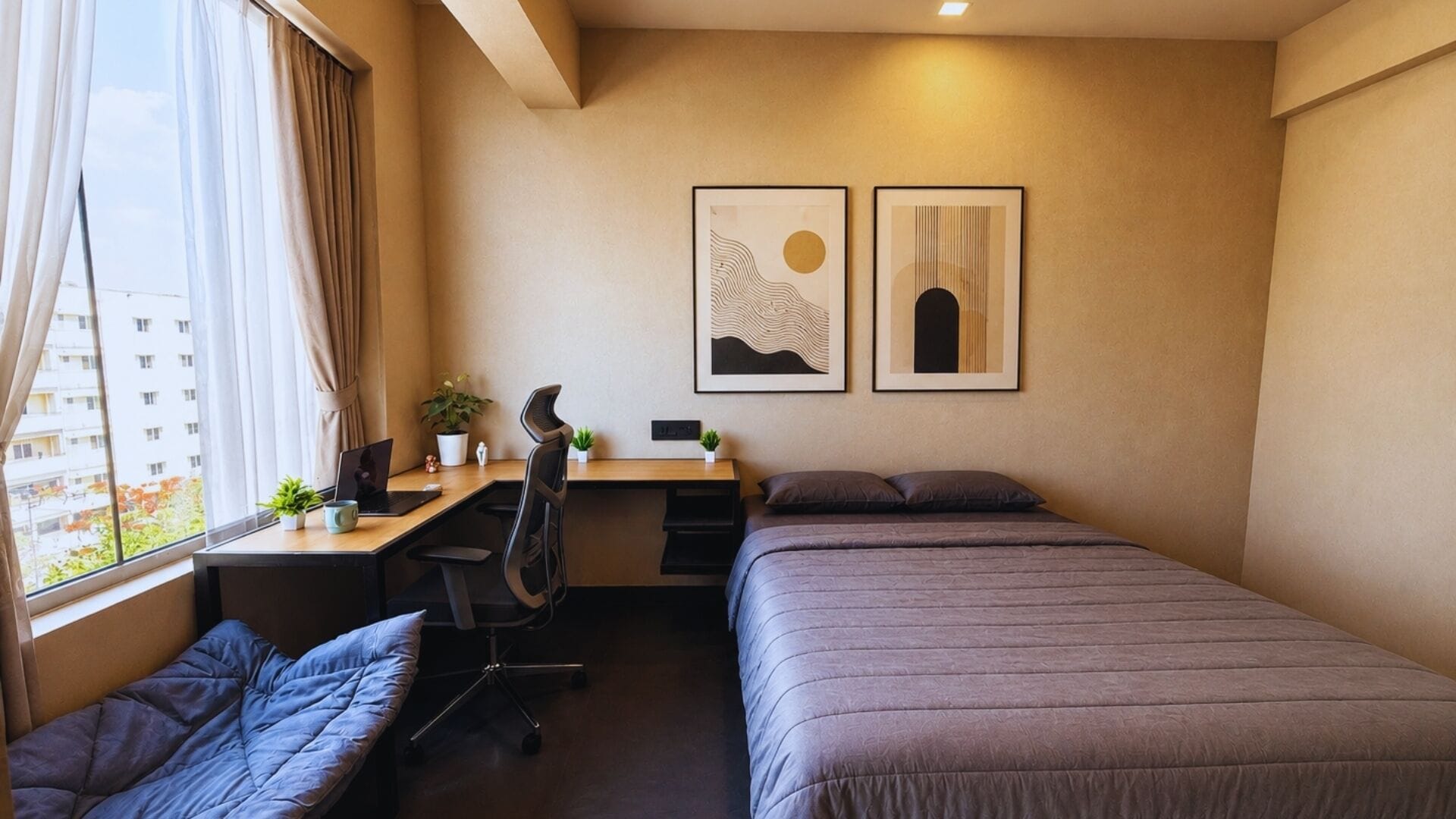 Un dormitorio con cama, escritorio, silla y dos cuadros en la pared.