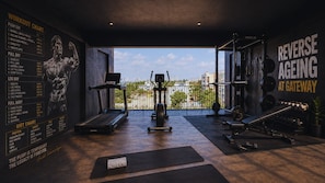 Un gimnasio con un cuadro de entrenamiento, equipo de ejercicio y vistas de la ciudad.