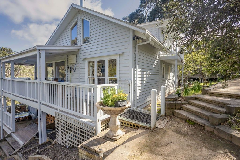 Une maison à deux étages avec un porche abrité et un petit jardin.