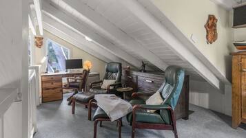 Ein Dachzimmer mit Schreibtisch, zwei Ledersesseln, einem kleinen Tisch und einem Schrank.
