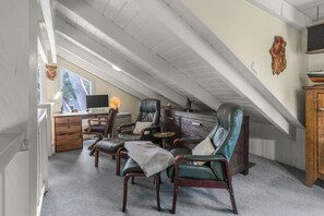 Ein Dachzimmer mit Schreibtisch, zwei Ledersesseln, einem kleinen Tisch und einem Schrank.