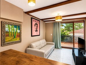 A living room with a sofa, a wooden table, a framed painting, a Vogue magazine, and a TV. - Central Bella Vista Apt w/ Terrace & Fast WiFi (Panama City)